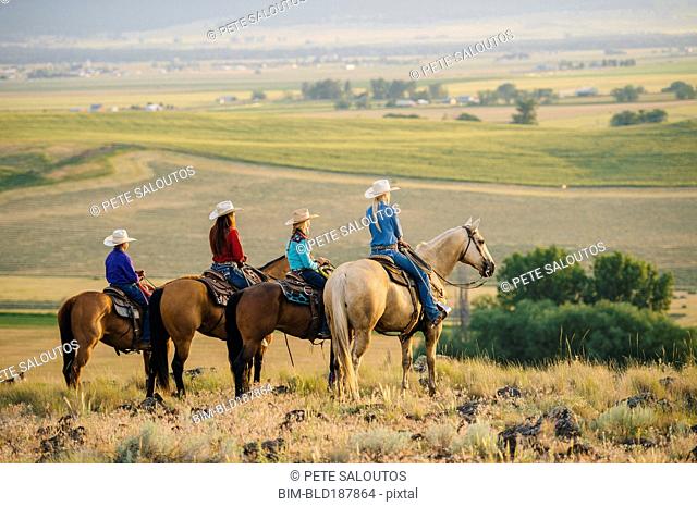 Cowboy and cowgirls on horseback admiring rural landscape