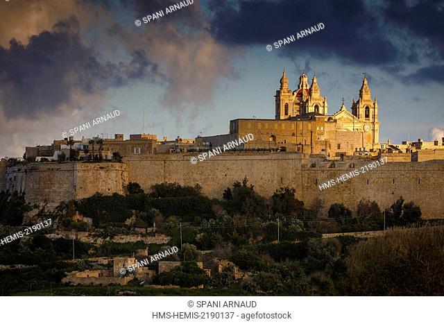 Malta, Mdina, panoramic views of the walls of a fortified city and its religious monuments at sunset under a cloudy sky