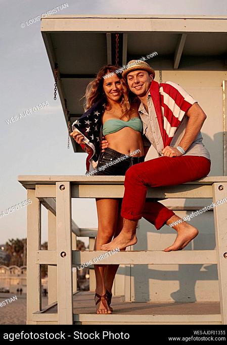 Couple with flag enjoying on vacations at Santa Monica beach