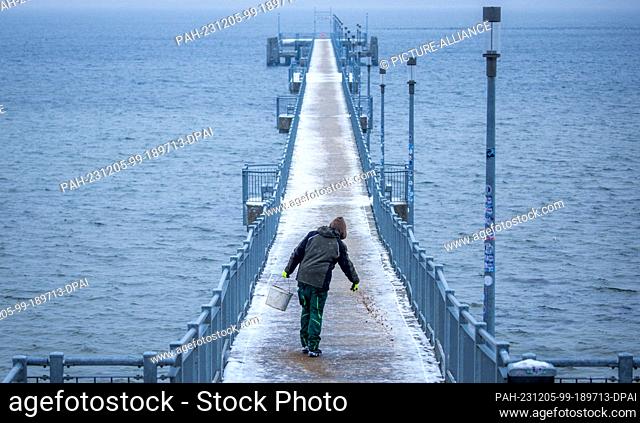 05 December 2023, Mecklenburg-Western Pomerania, Wismar: On the pier, the snow cover is spread with sand. Heavy snowfall and temperatures below freezing hinder...