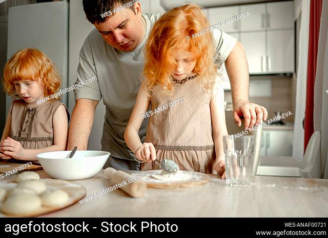 Father with daughters preparing cheesecake at home