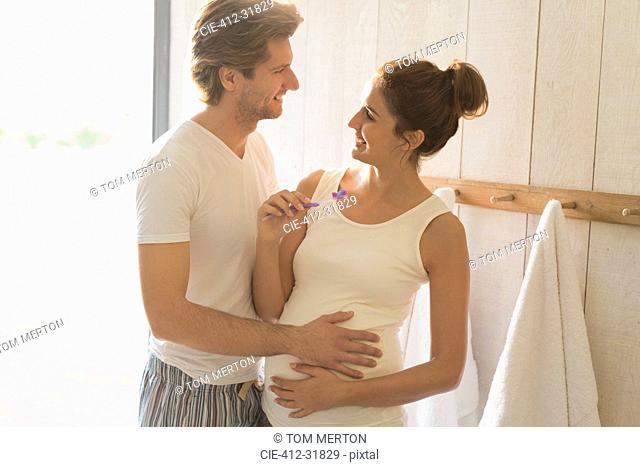 Pregnant couple brushing teeth in bathroom