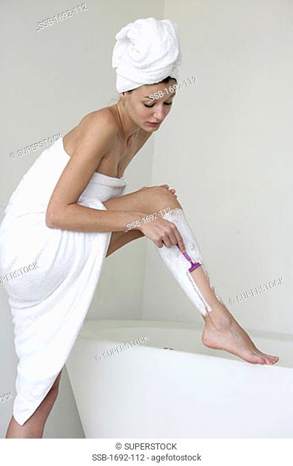 Young woman shaving her legs