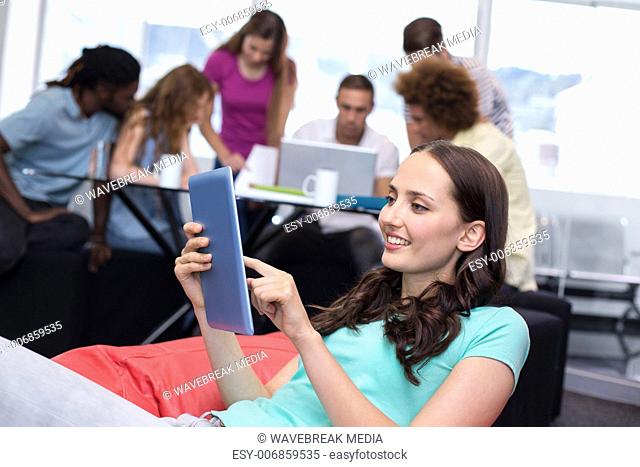 Student using digital tablet with friends in background