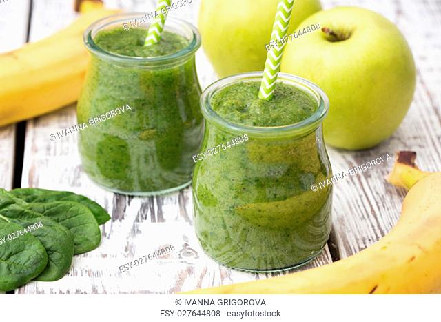 Green smoothie with apple, banana and spinach on a light background