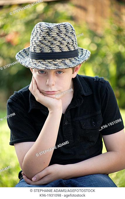 young boy sitting staring at camera with a grumpy face