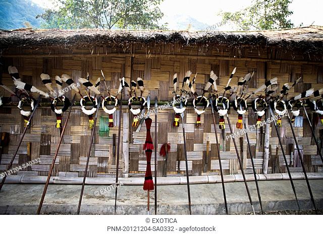 Feather headdresses with spears on the wall of a tribal hut, Kohima, Nagaland, India