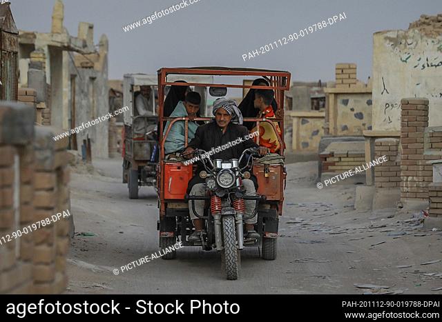 12 November 2020, Iraq, Najaf: A man rides a tricycle transporting visitors at Wadi al-Salam (Valley of Peace) cemetery in the Shiite holy city of Najaf