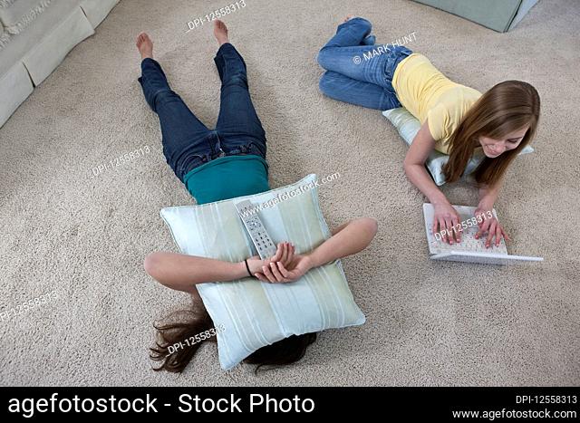 Two teenage girls with a remote control and laptop computer