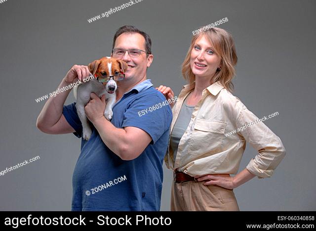 Happy woman and man in studio plays with jack russell terrier dog. Pet love concept