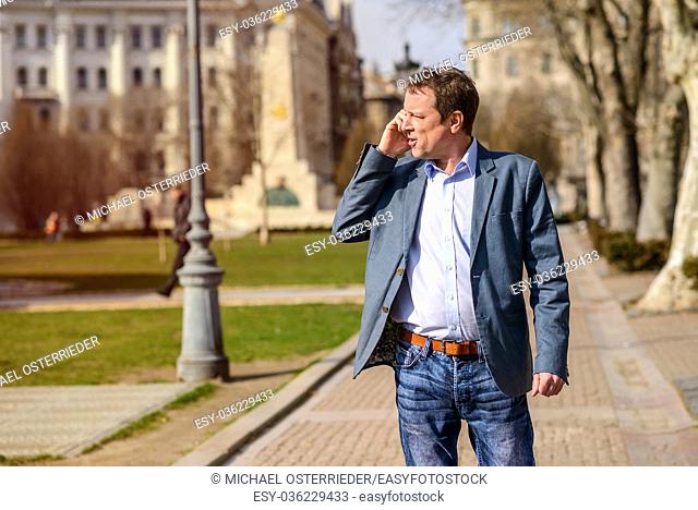 A middle age businessman walking in a park while talking on his phone