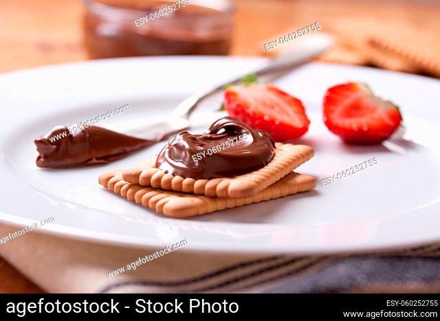 Chocolate sweet melting nougat cream on cookies with strawberries on a white plate, selective focus, closeup