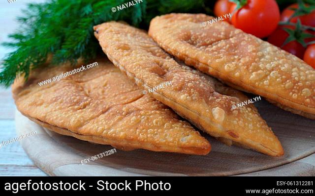 Cheburek with meat and cherry tomatoes. Traditional Romania, Ukrainian, Russian and Tatar food National east meal. Meat pie with beef, veal or lamb
