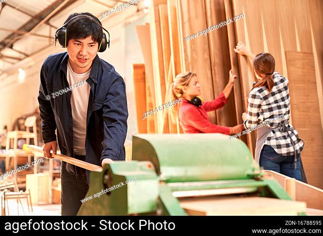 Junger Handwerker Lehrling beim Holz hobeln an der Dickenhobelmaschine