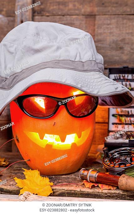 halloween pumpkin in hat with fly-fishing tackles