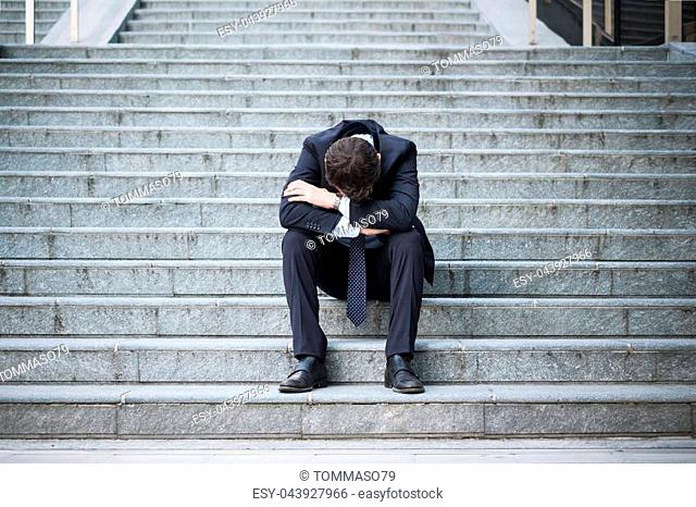 Desperate alone businessman after big fail sitting on the stairs