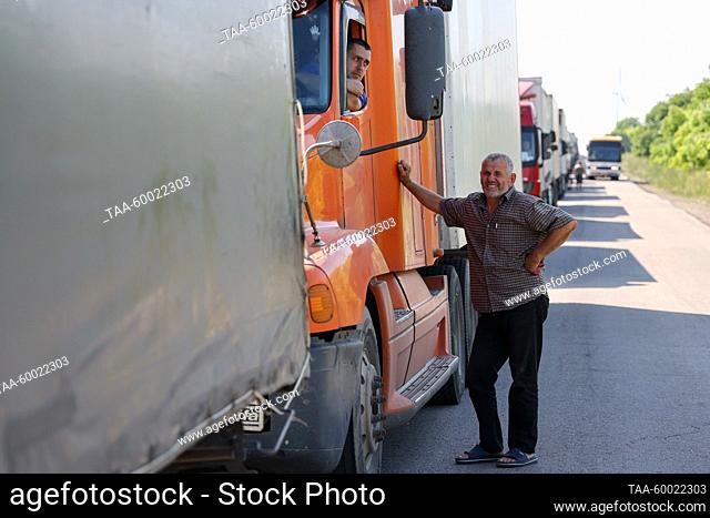 RUSSIA, KHERSON REGION - JUNE 23, 2023: A man leans against a truck as vehicles queue to pass the Armyansk checkpoint between the Kherson Region and Crimea