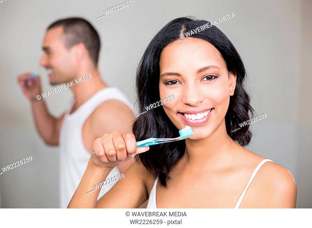 Couple brushing teeth in front of mirror