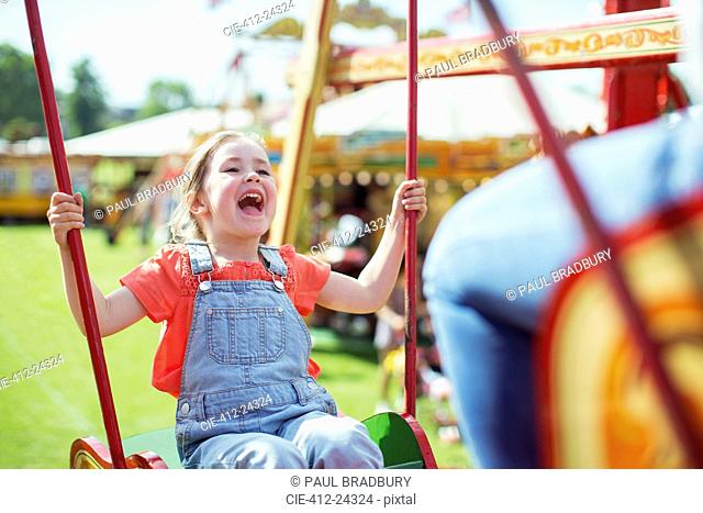 Cheerful girl laughing on carousel in amusement park