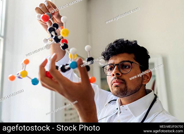 Young scientist analyzing helix model in laboratory