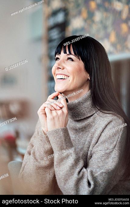 Happy woman looking away while sitting at cafe