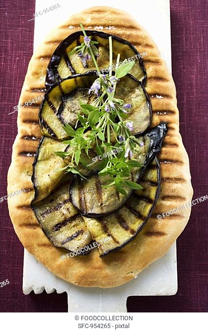 Grilled aubergine slices and herbs on pizza bread