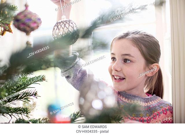 Girl decorating, hanging ornament on Christmas tree