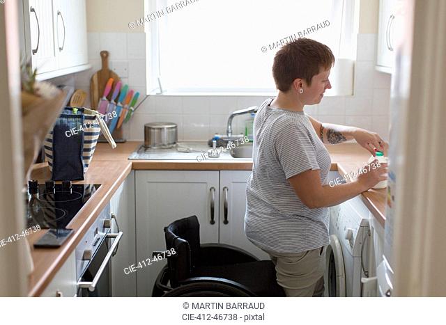 Young woman with wheelchair in apartment kitchen