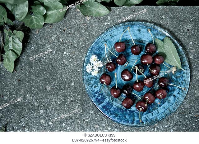 Delicious ripe cherry on blue plate on grey stone flat lay Healthy fruit eating Top view