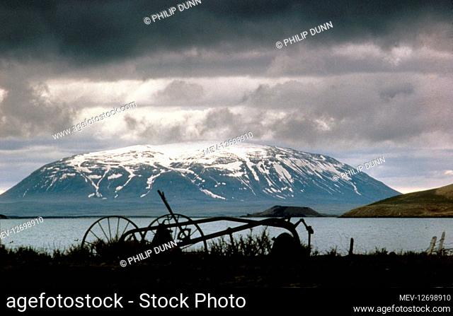 An old farm implement on the banks of Myvatn Lake, Iceland. Snow covered Sellandafjall mountain is in the background
