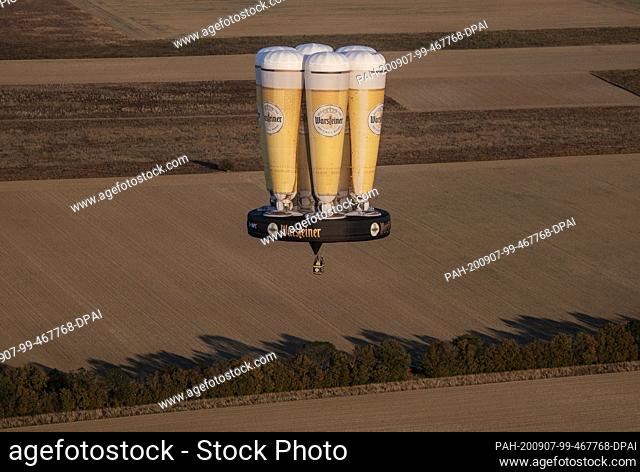 07 September 2020, North Rhine-Westphalia, Bad Sassendorf: A hot-air balloon in the form of a tray with six beer tulips standing on it rides across the sky on...