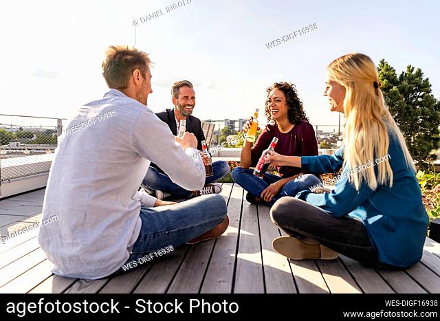 Happy colleagues toasting drinks on rooftop