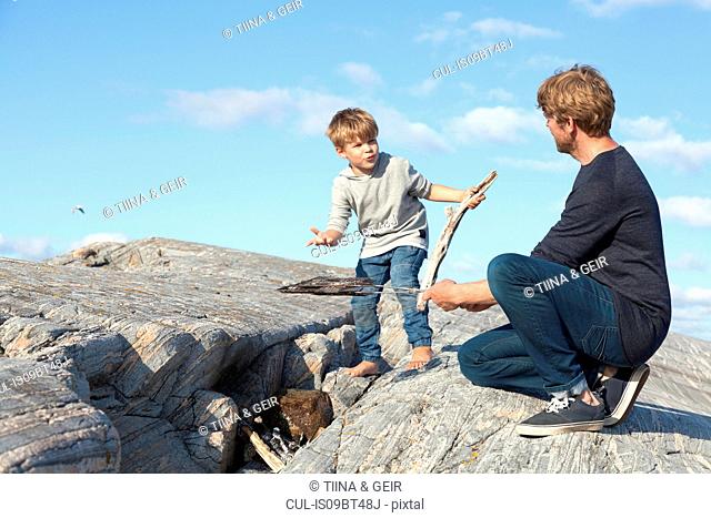 Boy and father preparing campfire on inlet rock, Aure, More og Romsdal, Norway