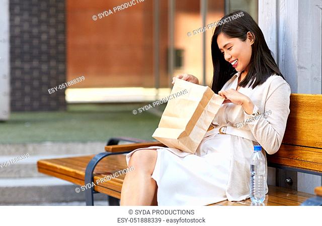 woman with takeaway lunch in paper bag in city