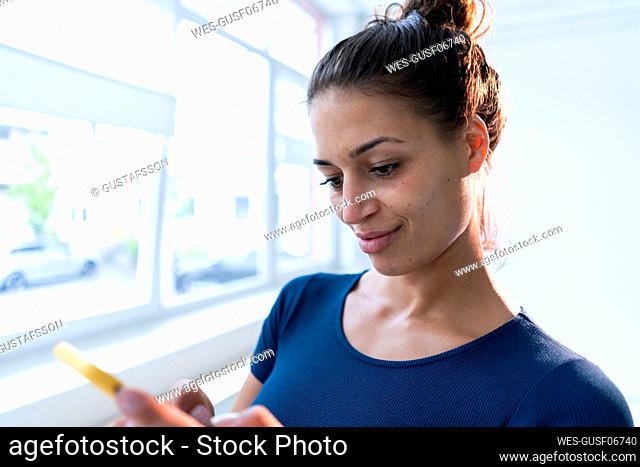 Woman using smart phone near window