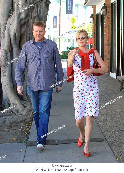 Melanie Griffith dressed in a co ordinated cherry motif dress complimented with red shoes and red sweater is out and about with a male companion