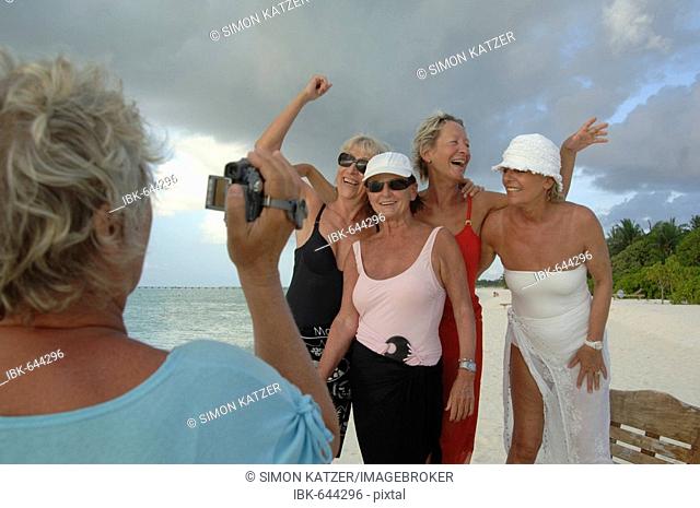 Elderly women filming each other with a video camera on the beach, Diffushi Island, Holiday Island, Southern Ari Atoll, Maldives, Indian Ocean