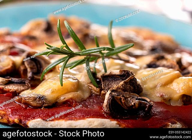Rosmarin auf einer Pilzpizza auf einem Teller