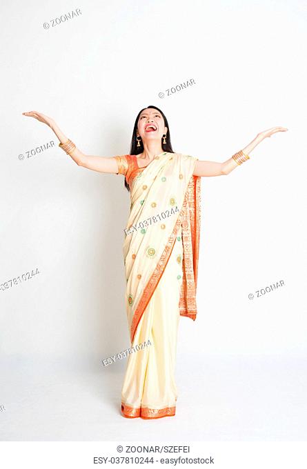 Woman in Indian sari dress hand raised looking up