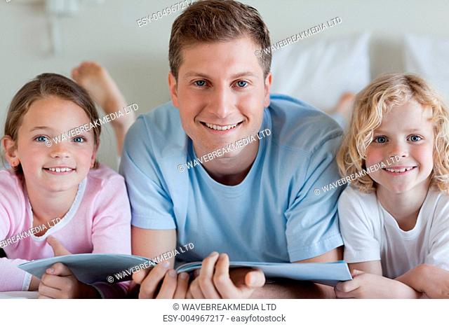 Smiling father with his children and a magazine