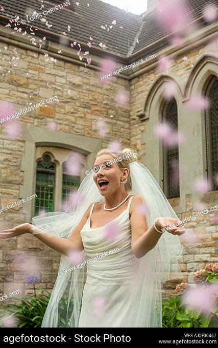 Surprised young bride standing amidst petal confetti at church