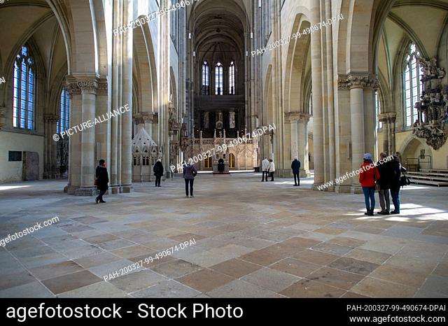 26 March 2020, Saxony-Anhalt, Magdeburg: Believing Christians stand at midday prayer in the unseated nave of the Magdeburg Cathedral at a distance from each...