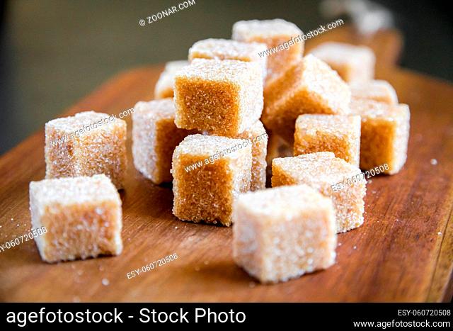 Brown cane sugar cubes on a wooden cutting board