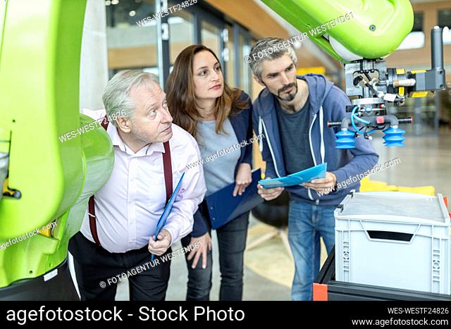 Technicians showing new industrial robot to senior colleague