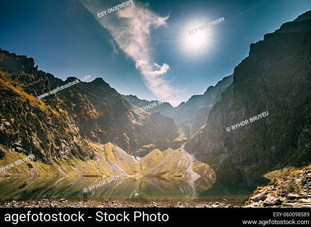 Tatra National Park, Poland. Calm Lake Czarny Staw Under Rysy And Summer Mountains Landscape. Sunshine With Sunrays Above Beautiful Scenic View Of Lake