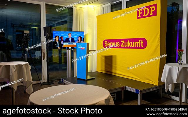 08 October 2023, Bavaria, Munich: Markus Söder (CSU), Prime Minister of Bavaria, is seen on a screen behind empty bar tables at the FDP's election party at the...