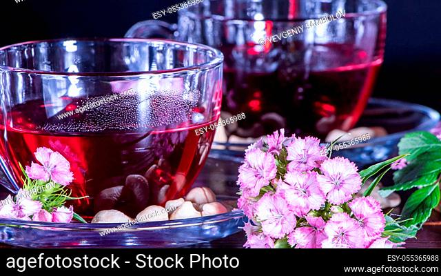 Hibiscus Red tea mug with carnation flowers close-up horizontal photo.English tea tradition.Medicinal therapy based on medicinal herbs and decoctions