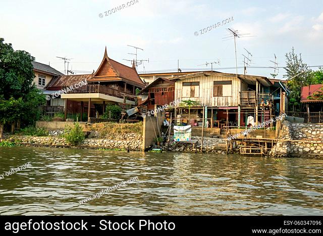 Chao Phraya houses and boats on the riverside during sunset hours taken from the boat ride. Ayutthaya, Thailand