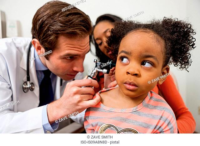 Mid adult doctor using otoscope on patient