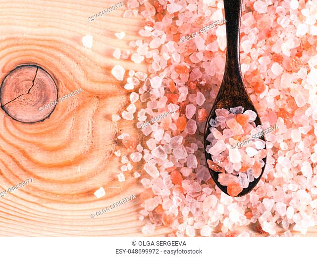 Himalayan pink salt in spoon on wooden background. Copy space